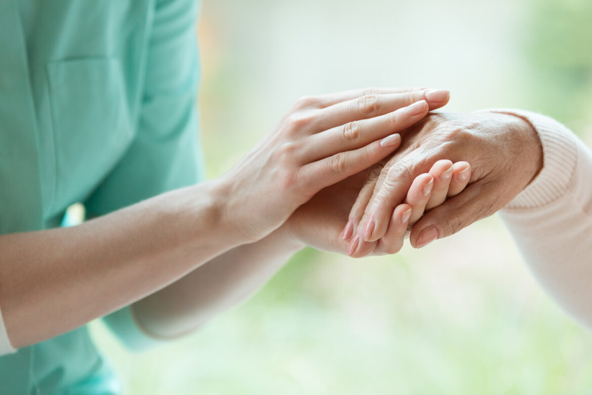 Caretaker massaging pensioner’s hand La fisioterapia en cuidados paliativos
